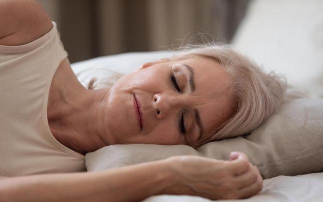 Señora duerme plácidamente en su cama.