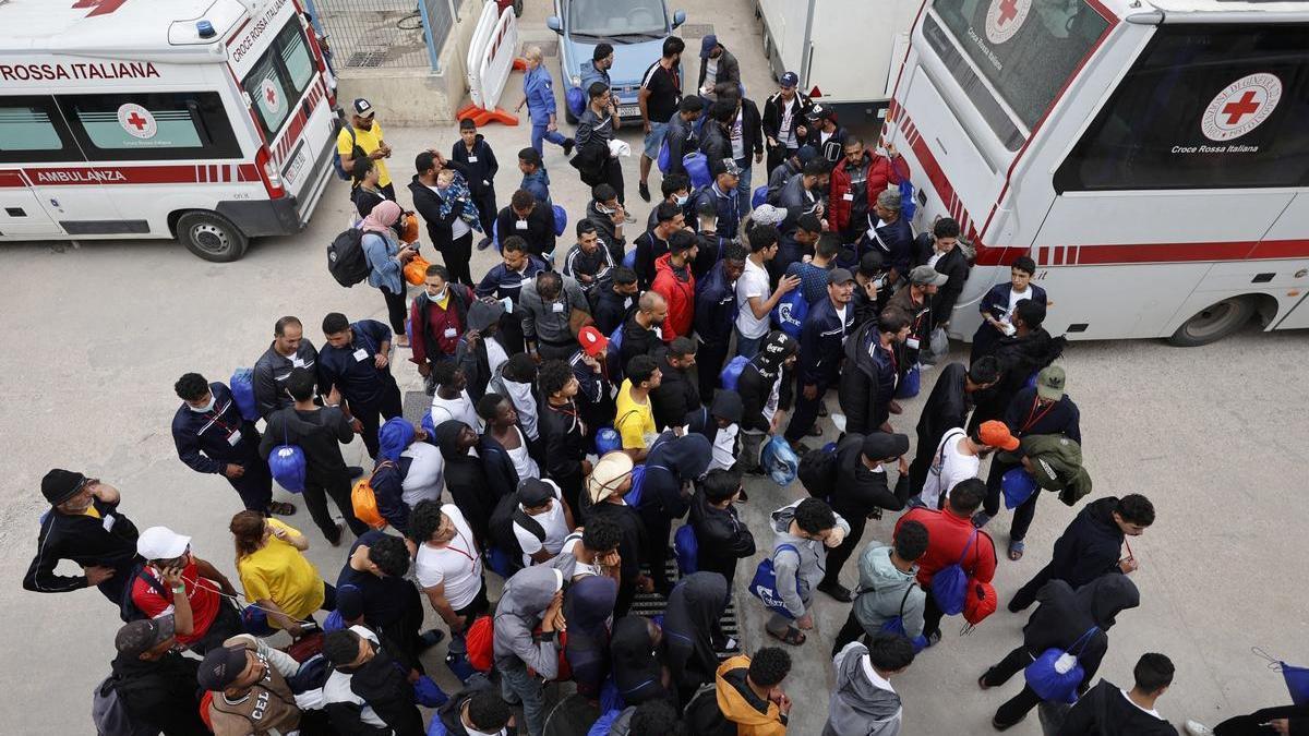 Un grupo de migrantes espera frente al centro de recepción de Lampedusa.