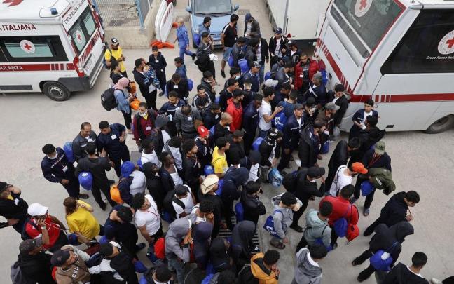 Un grupo de migrantes espera frente al centro de recepción de Lampedusa.