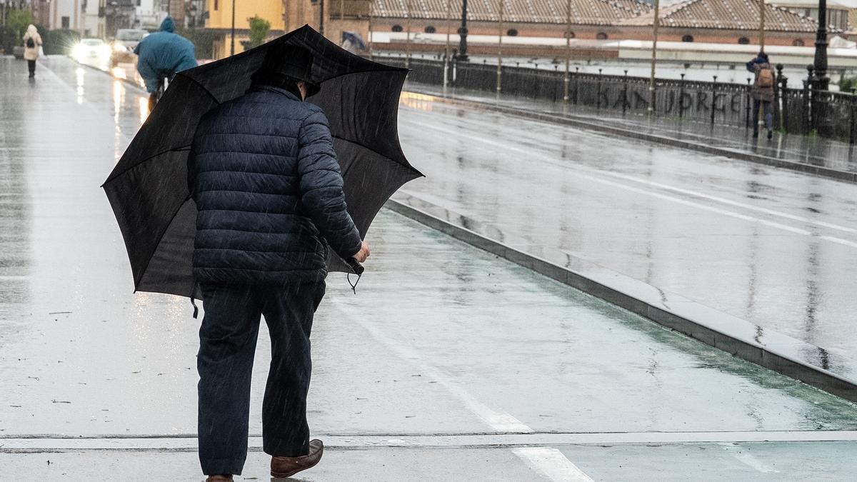 Un hombre hace frente al viento con un paraguas.