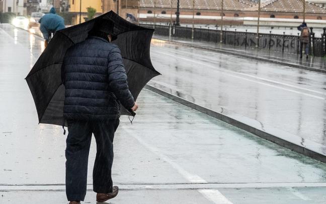Un hombre hace frente al viento con un paraguas.