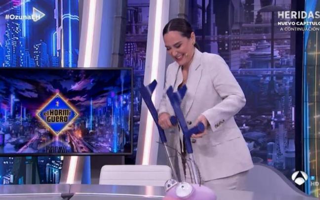 Tamara Falcó, entrando al plató con muletas mientras en el rótulo anuncian un programa muy acorde..