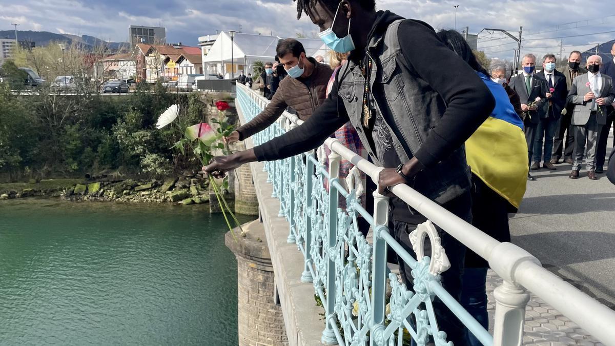 Un migrante realiza una ofrenda floral en el río Bidasoa.