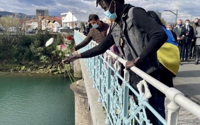 Un migrante realiza una ofrenda floral en el río Bidasoa.