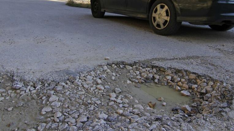Un vehículo pasa junto a un bache