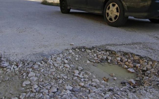 Un vehículo pasa junto a un bache