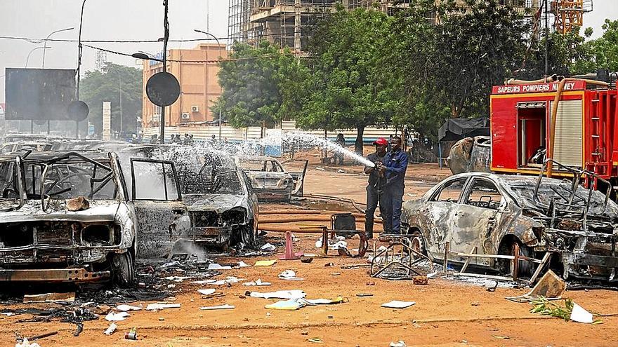 Bomberos tratan de sofocar el incendio en varios coches calcinados en las protestas por el golpe. | FOTO: EFE