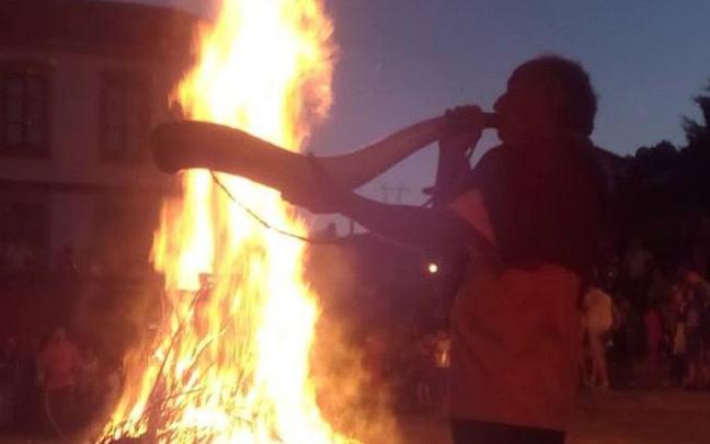 El maestro artesano Alaña toca el cuerno con la hoguera del soslticio de verano de fondo en Artziniega