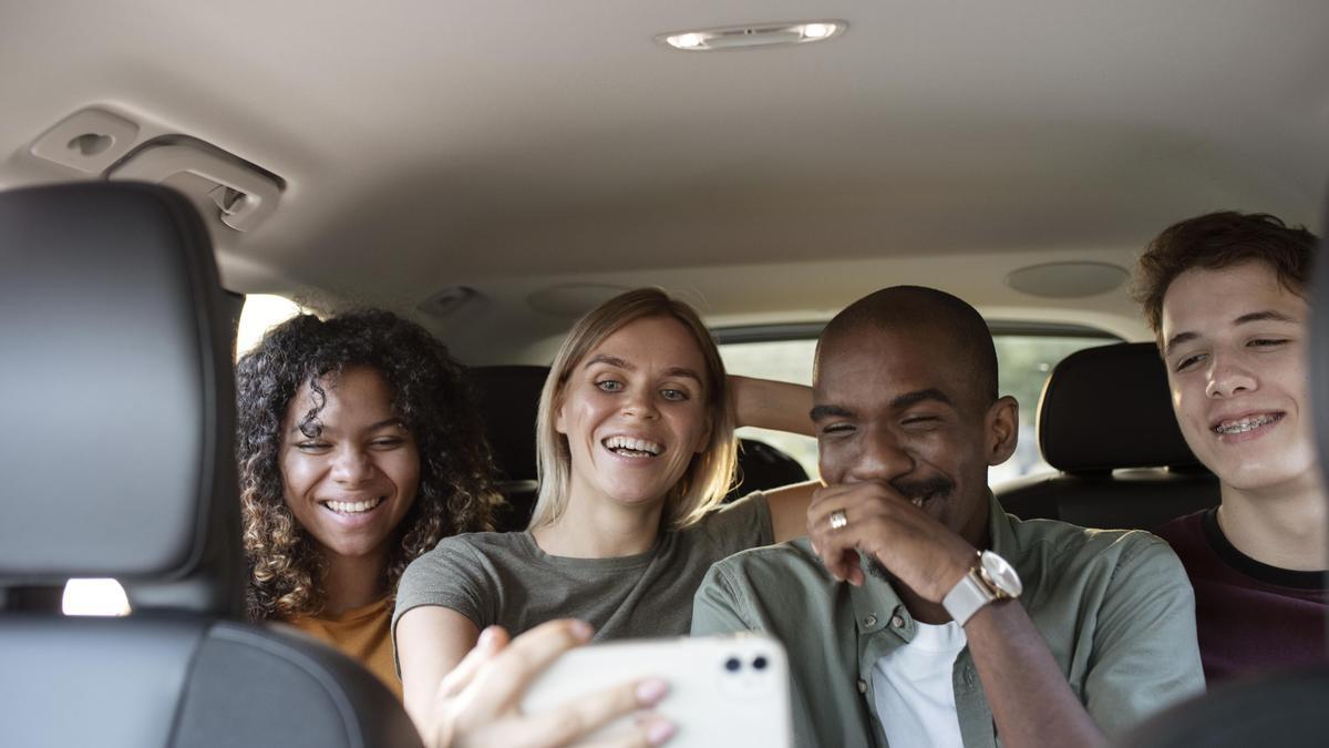 Tres jóvenes parecen divertirse en un coche.