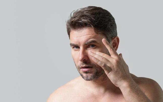 Un hombre se aplica un bálsamo para las arrugas ante un espejo. Un hombre se aplica un bálsamo para las arrugas ante un espejo.