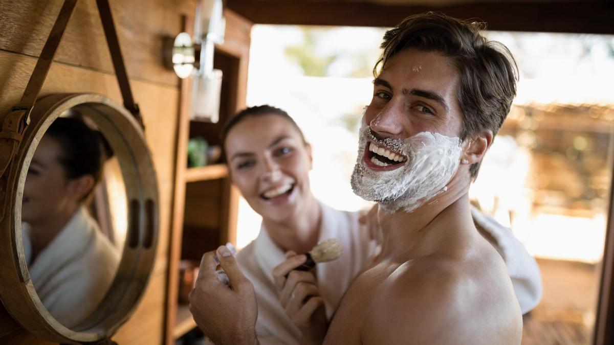 Un hombre sonríe divertido mientras se afeita en una cabaña.