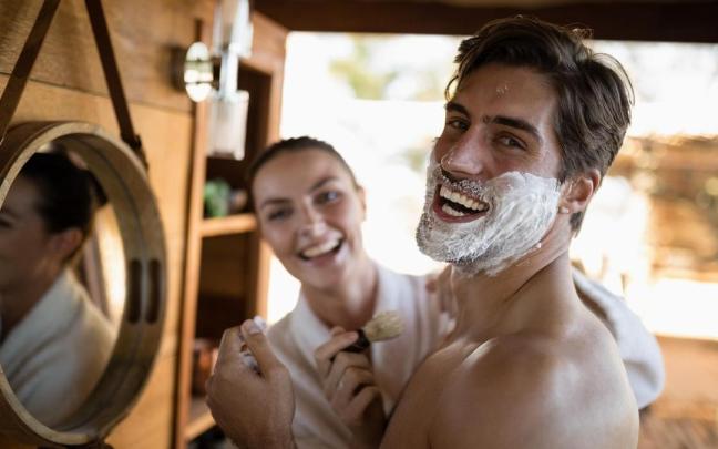 Un hombre sonríe divertido mientras se afeita en una cabaña.