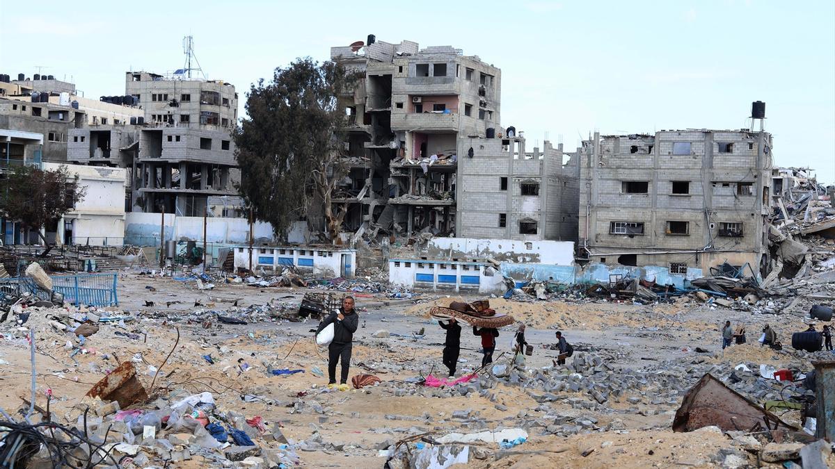 Un grupo de palestinos camina entre edificios dañados por los bombardeos del Ejército de Israel en la ciudad de Rafá, en el sur de la Franja de Gaza.