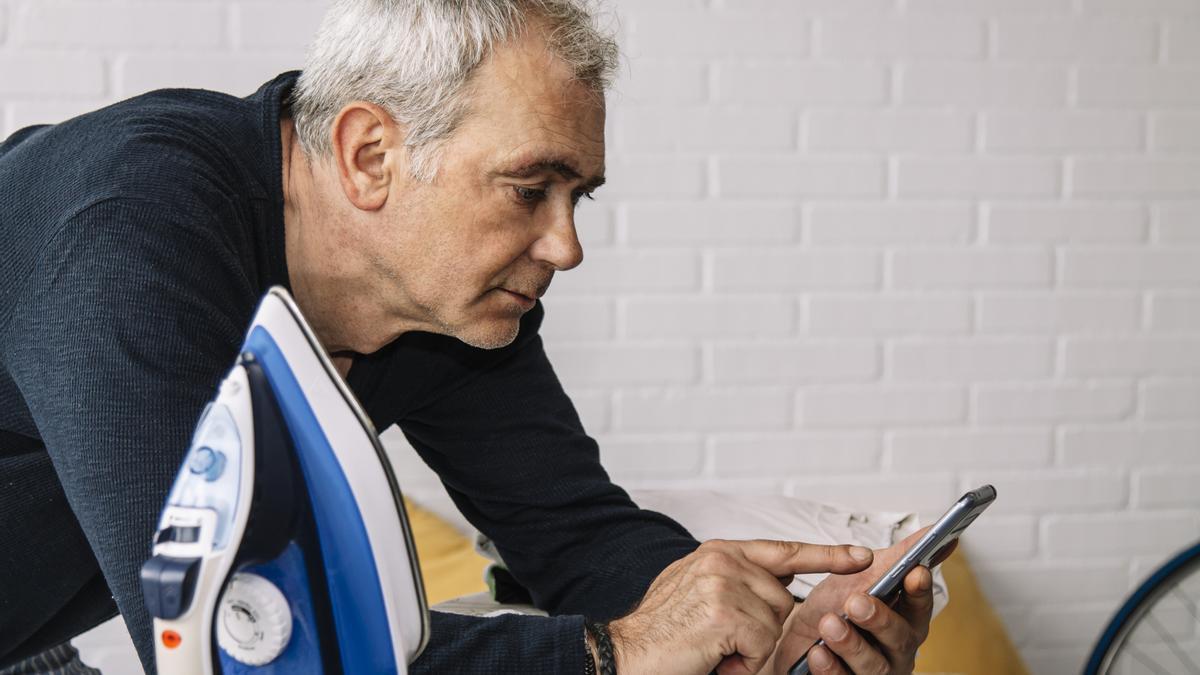 Un señor ajeno a esta historia mira su teléfono móvil con la plancha al lado.