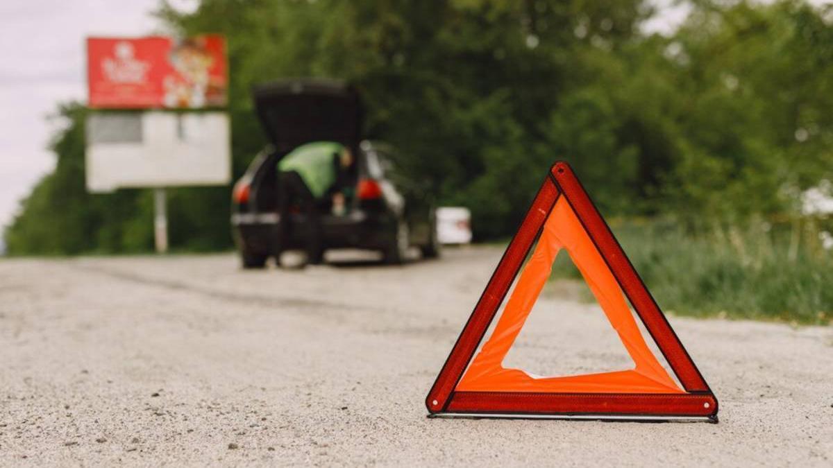 Coche con problemas y un triángulo rojo para advertir a otros usuarios de la carretera