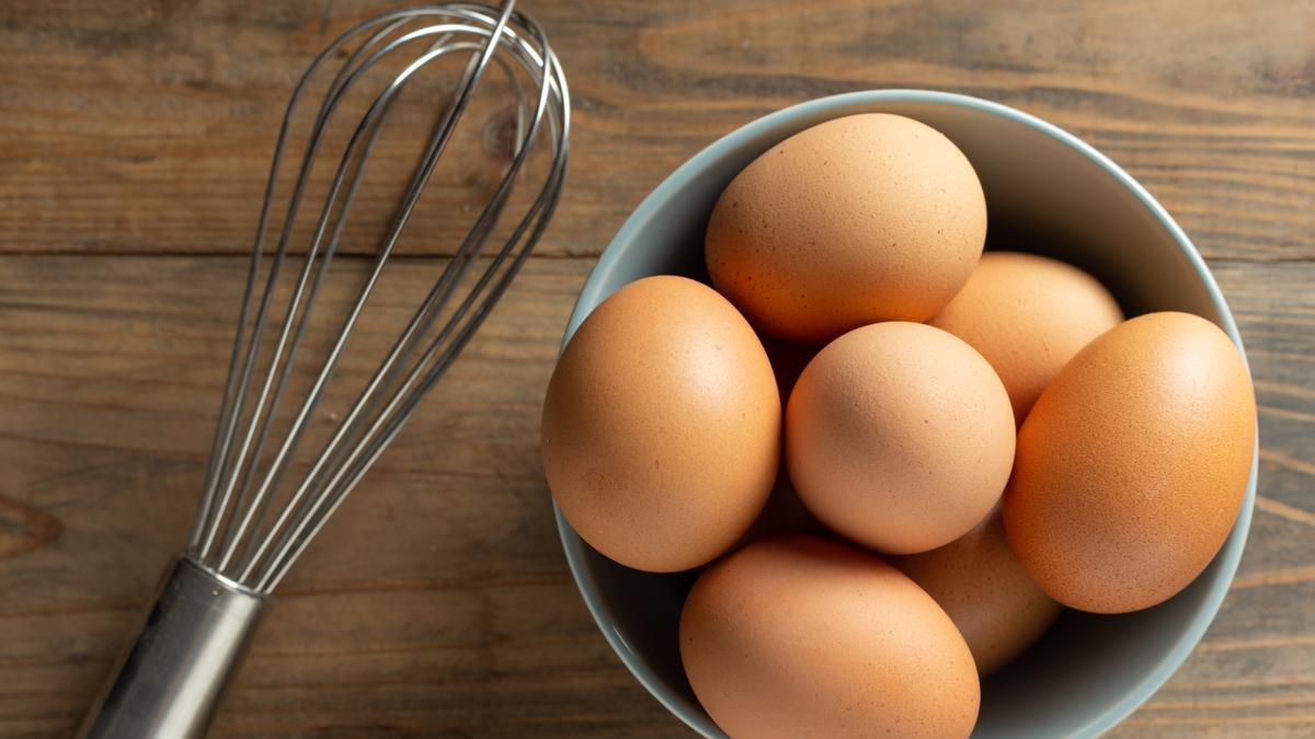 Huevos en un bol junto a una varilla para batir