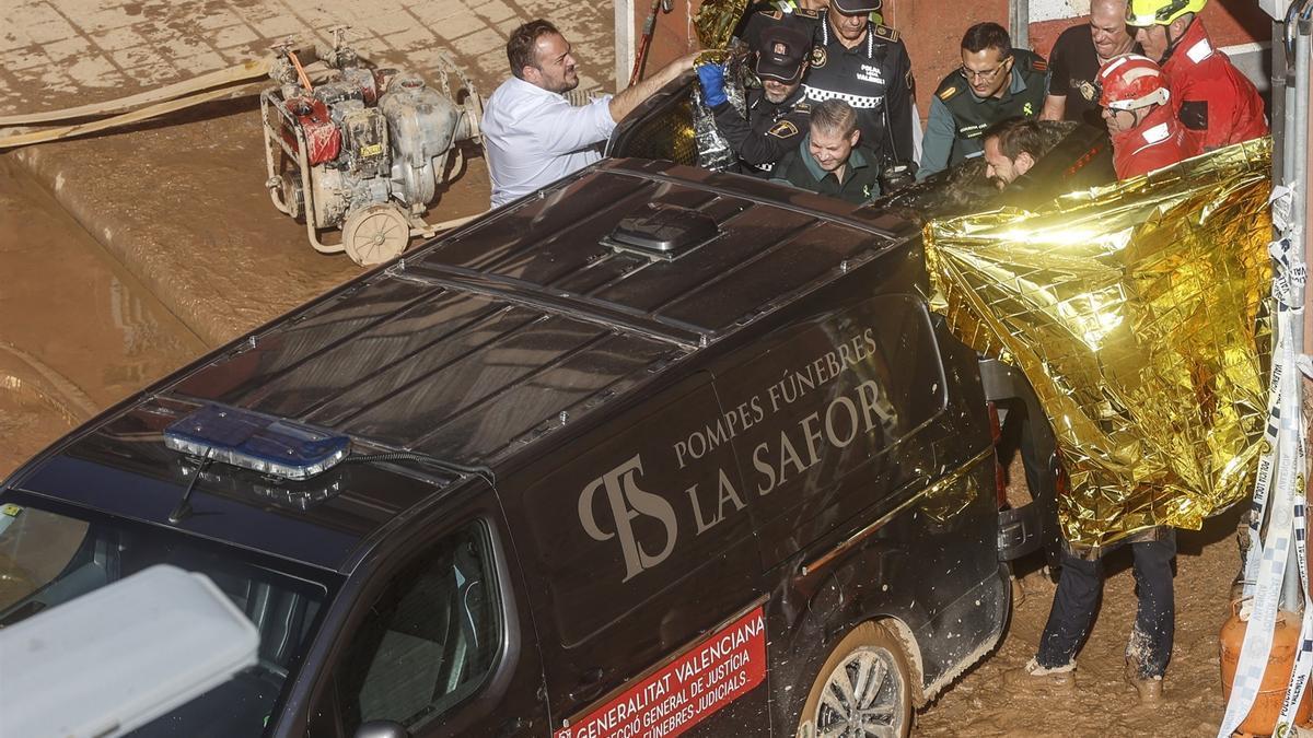 Un furgón de la funeraria sale de un garaje con cadáveres localizados tras el paso de la DANA.