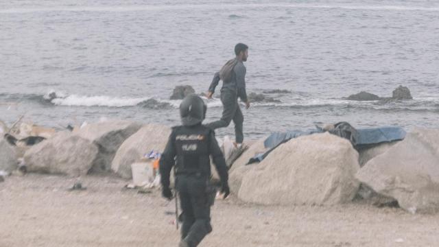 Un migrante huye de un policía en Ceuta.