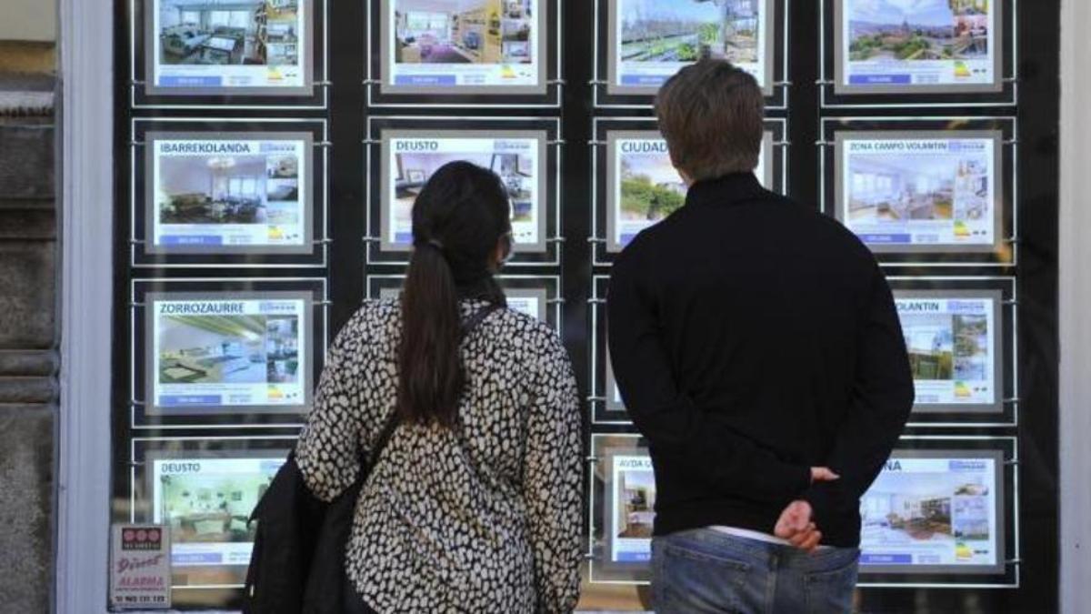 Dos personas observan el exterior de una inmobiliaria en Euskadi