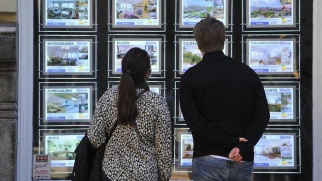 Dos personas observan el exterior de una inmobiliaria en Euskadi