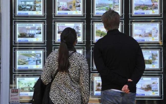 Dos personas observan el exterior de una inmobiliaria en Euskadi