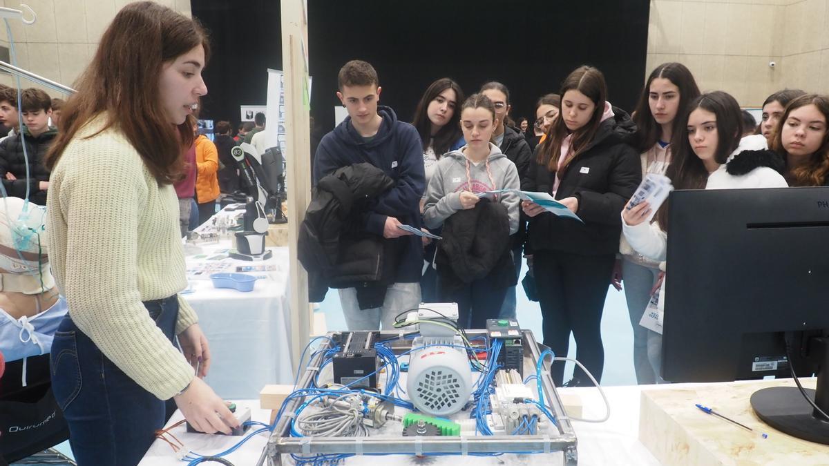 Un grupo de estudiantes atiende a las explicaciones sobre el funcionamiento de una máquina en la feria de la FP