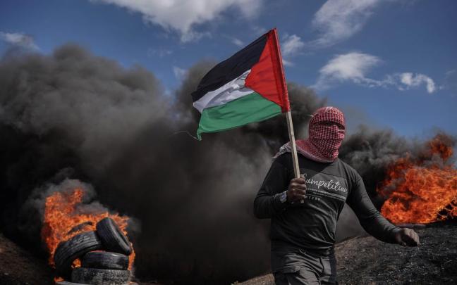 Un manifestante sostiene una bandera palestina durante una protesta. Un manifestante sostiene una bandera palestina durante una protesta.