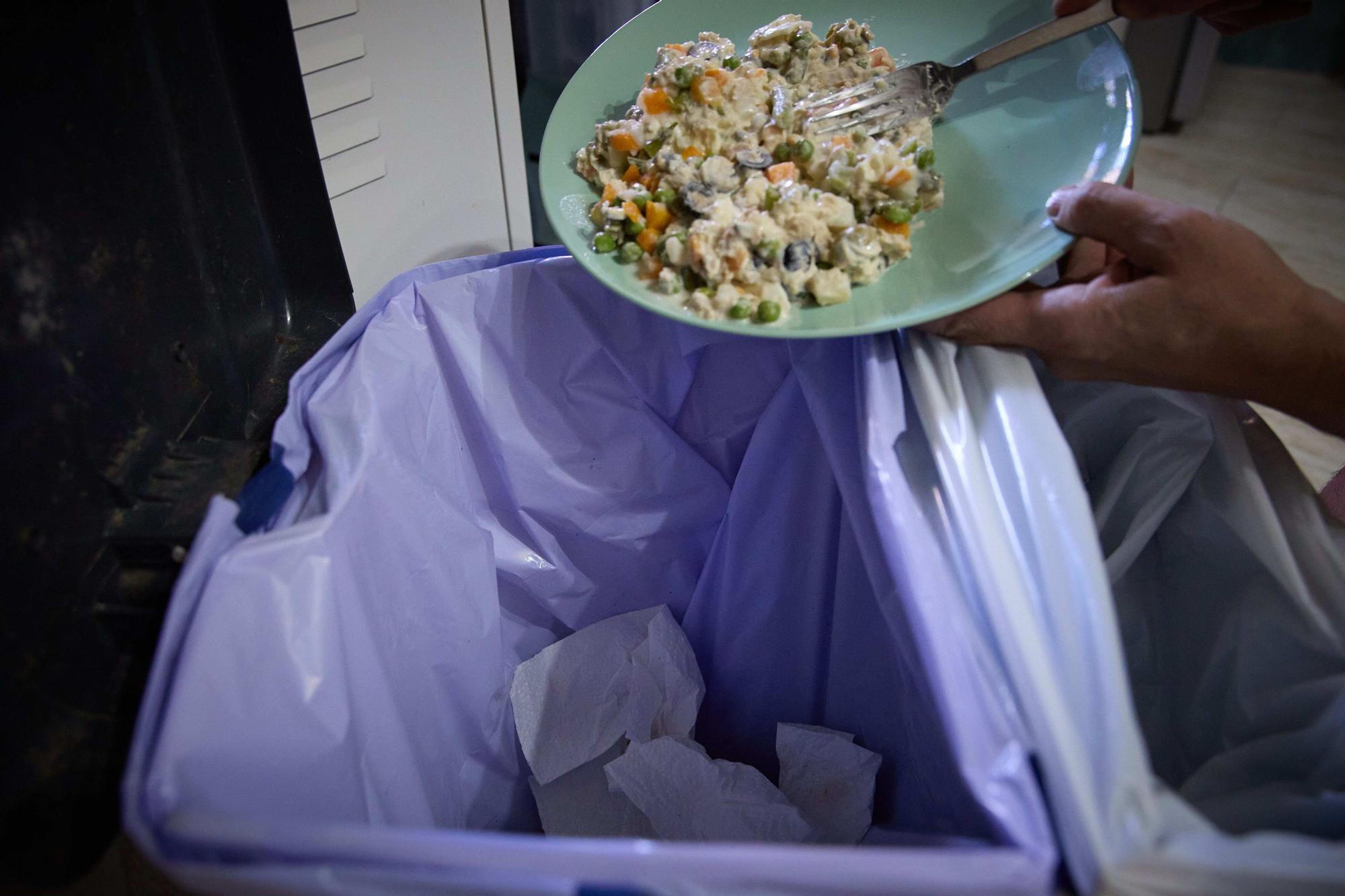 Una persona tira comida a la basura.