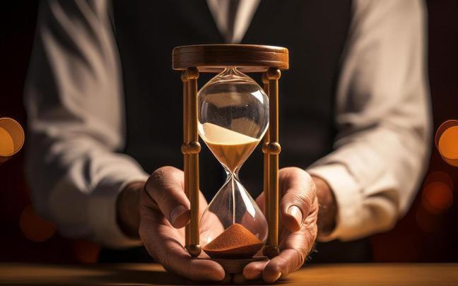 Un hombre de mediana edad sostiene entre sus manos un reloj de arena. Un hombre de mediana edad sostiene entre sus manos un reloj de arena.