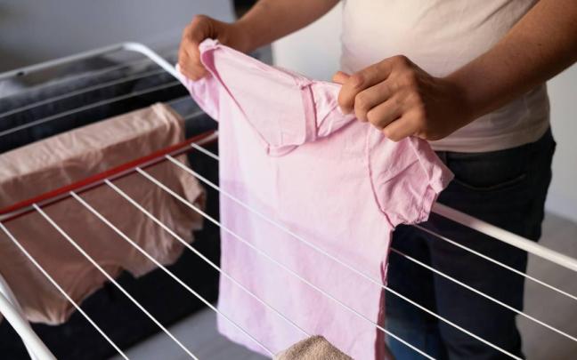 Colgar la ropa en un tendedero plegable.