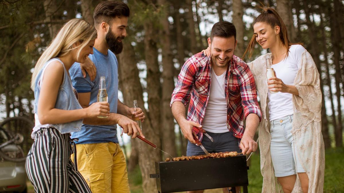 Cuatro amigos asan carne en el campo.