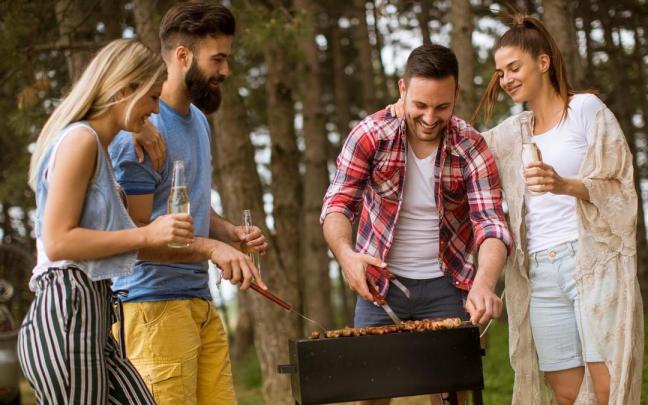 Cuatro amigos asan carne en el campo.