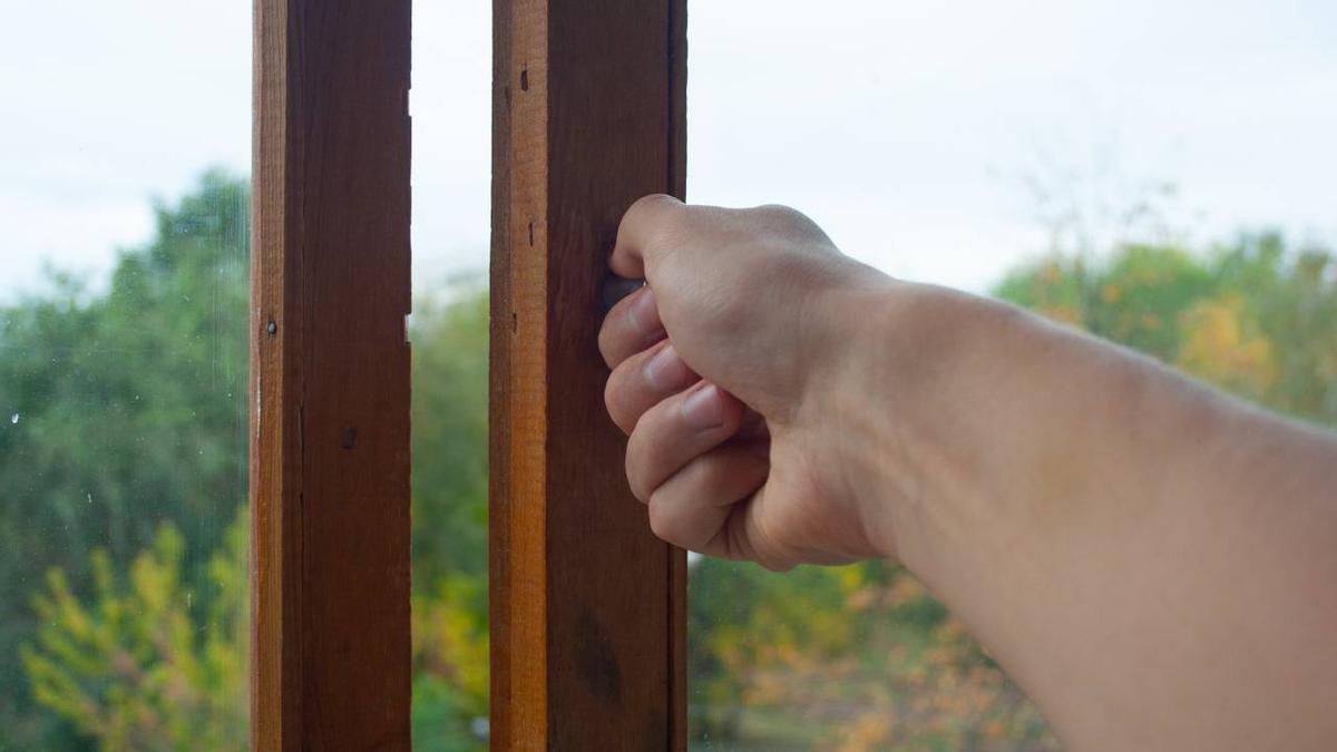 Primer plano de una mano abriendo una ventana