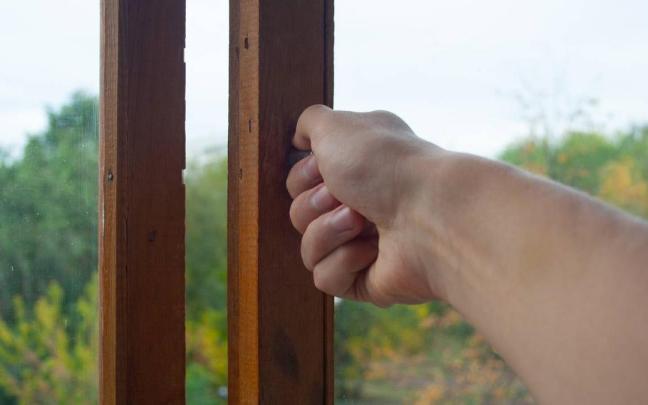 Primer plano de una mano abriendo una ventana