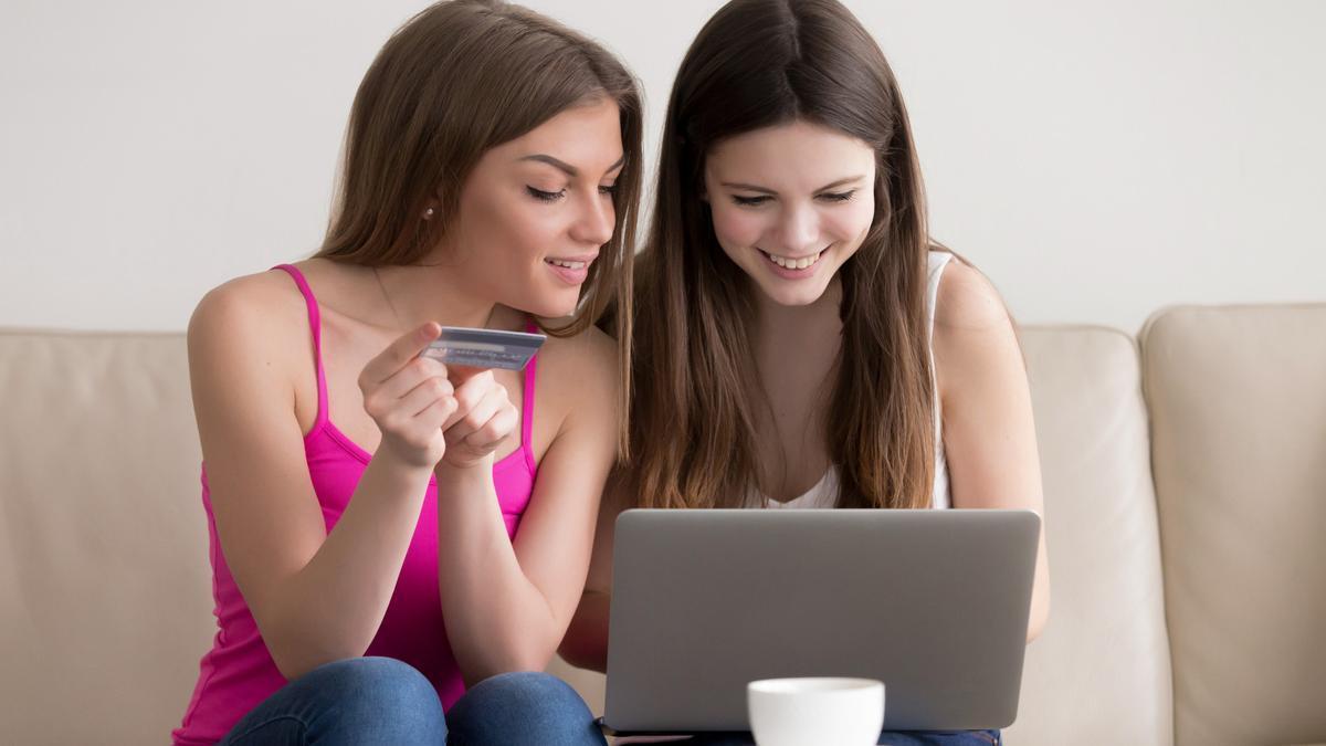 Dos adolescentes compran con una tarjeta de crédito a través de un portátil.