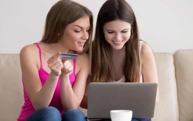 Dos adolescentes compran con una tarjeta de crédito a través de un portátil.