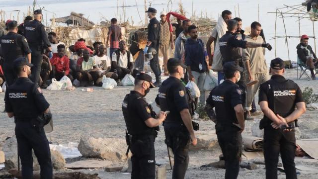 Agentes proceden al traslado de los migrantes que permanecían en la playa del Trampolín.