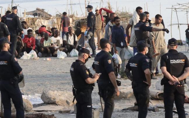 Agentes proceden al traslado de los migrantes que permanecían en la playa del Trampolín.