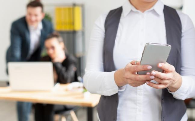 Una persona usa su teléfono móvil durante la jornada laboral