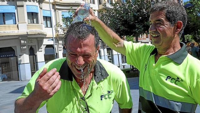 Dos trabajadores de FCC, refrescándose con una botella de agua para hacer frente a la ola de calor.