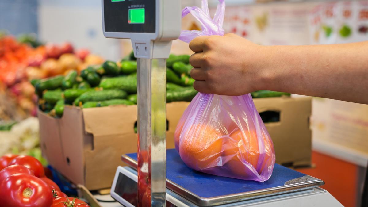Una persona pesa unas frutas en un supermercado.