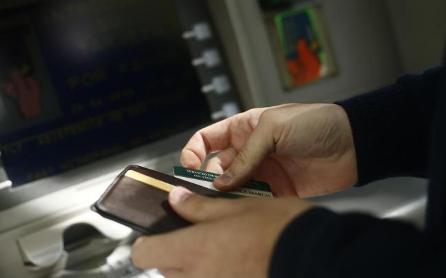 Una persona saca dinero en un cajero. Una persona saca dinero en un cajero.