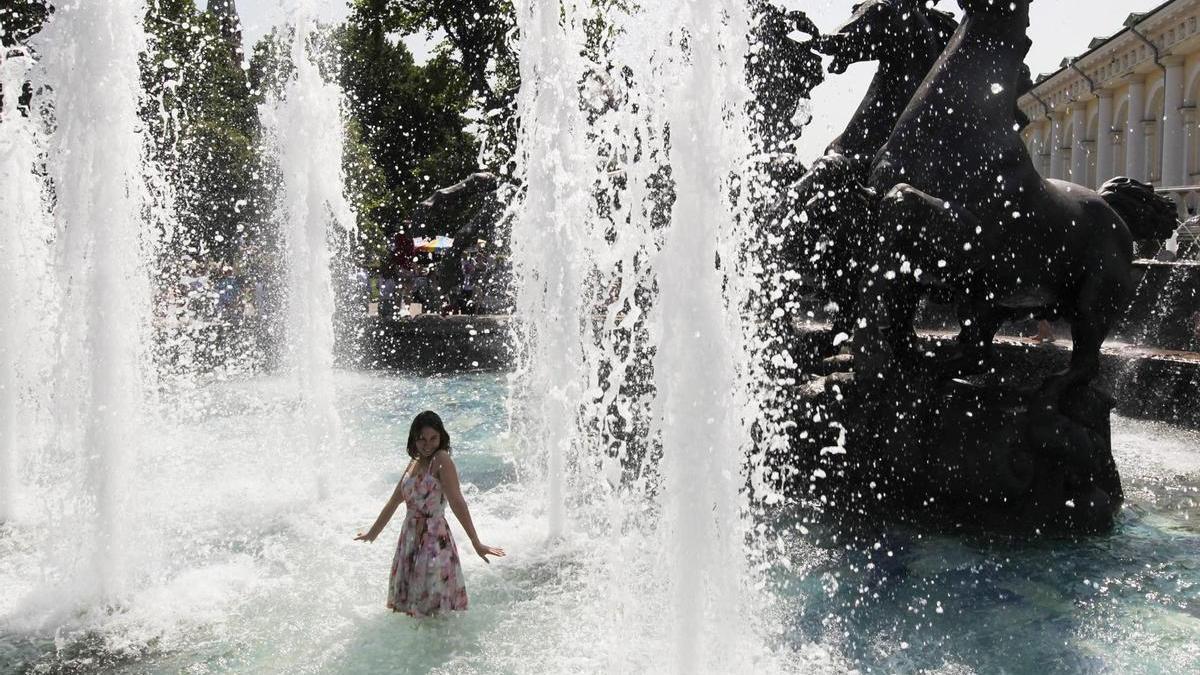 Una joven se refresca en una fuente para combatir el calor cerca del Kremlin, en Moscú.