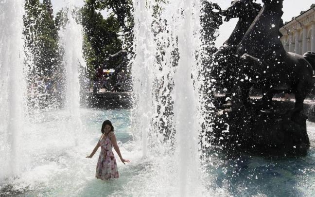 Una joven se refresca en una fuente para combatir el calor cerca del Kremlin, en Moscú.