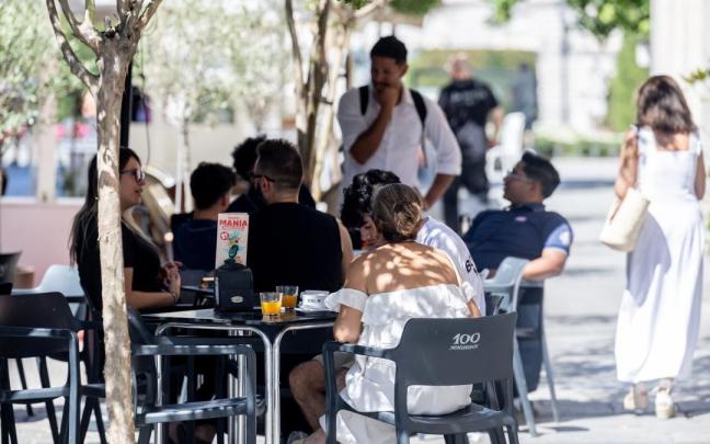 Clientes de un bar se refrescan en la terraza.