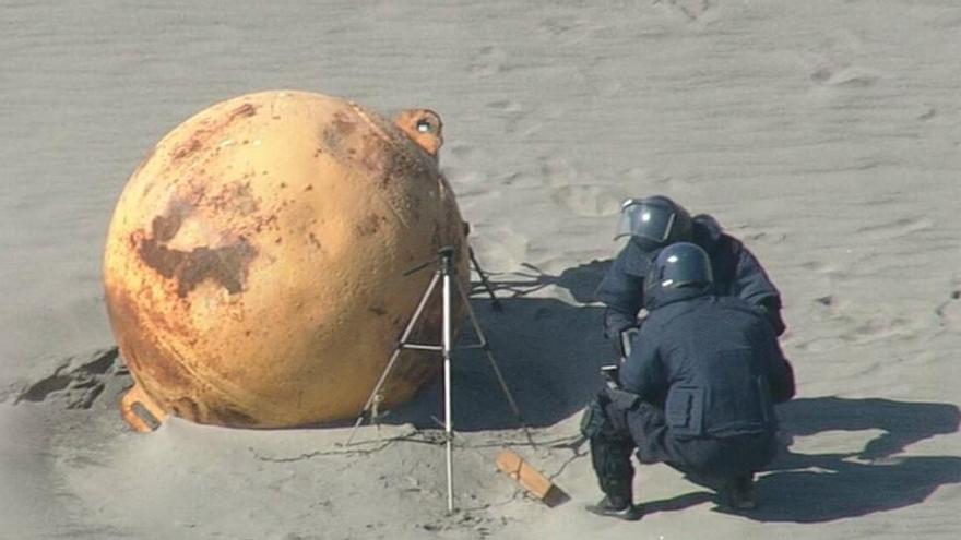 Dos agentes estudian la gigantesca bola en la playa.