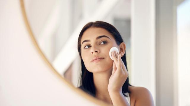 Una mujer se limpia el rostro con un disco de desmaquillar.