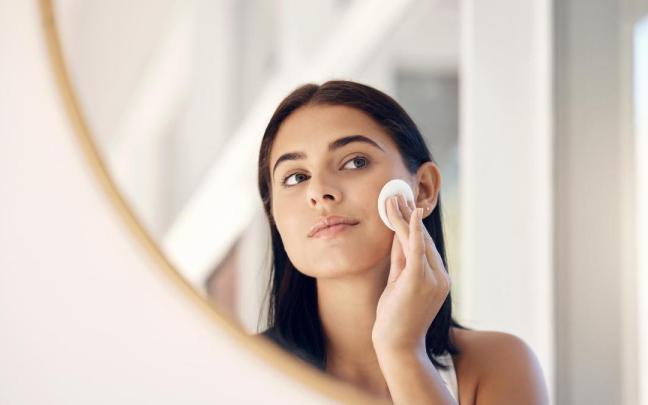 Una mujer se limpia el rostro con un disco de desmaquillar.