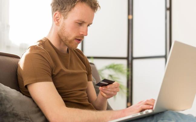Un hombre realiza una compra online con una tarjeta de crédito.