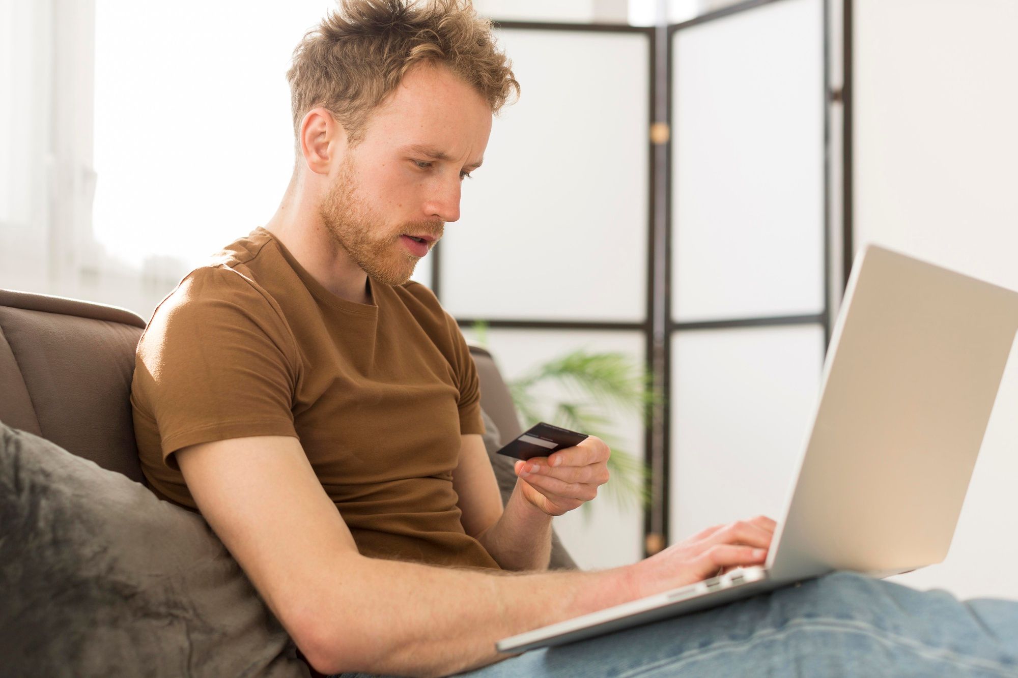 Un hombre realiza una compra online con una tarjeta de crédito.